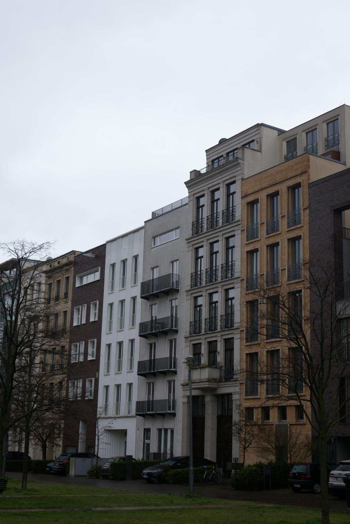 Straßenzug mit mehrgeschossigen Wohnhäusern unter bewölktem Himmel